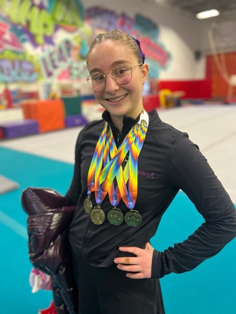 A smiling gymnast wearing four medals